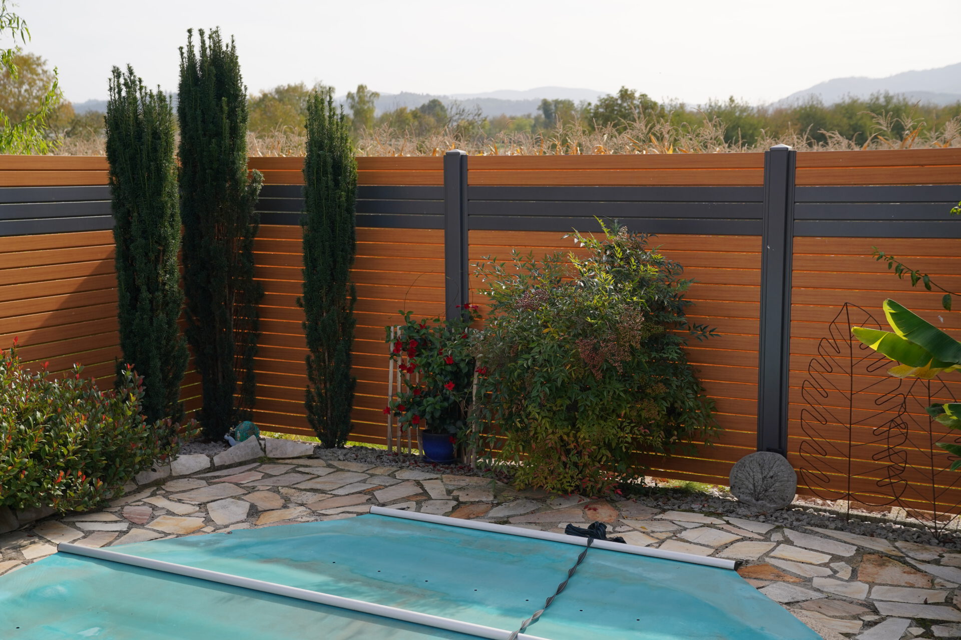 DSC03549 Terrassenabtrennung Titelbild - Eine Aluminium Terrassenabtrennung in einem Braun - Anthrazit Ton umschließt den Terrassenbereich eines Gartens.